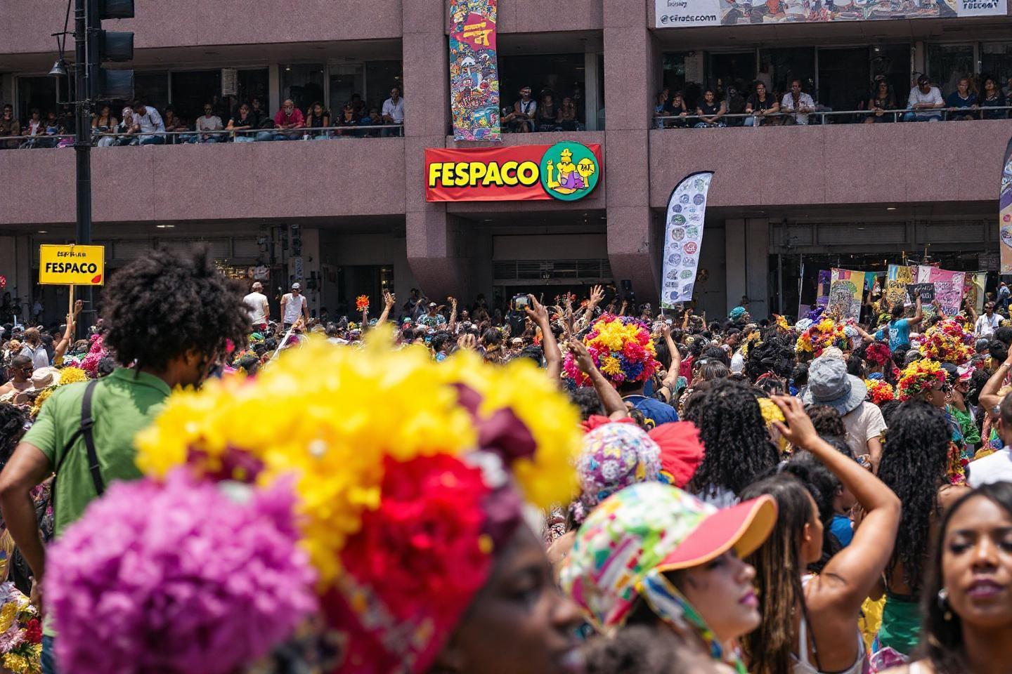 Foule colorée au festival Fespaco avec des participants en fleurs