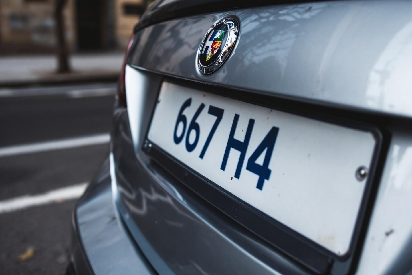 Détail de la plaque et du logo Alfa Romeo sur une voiture grise