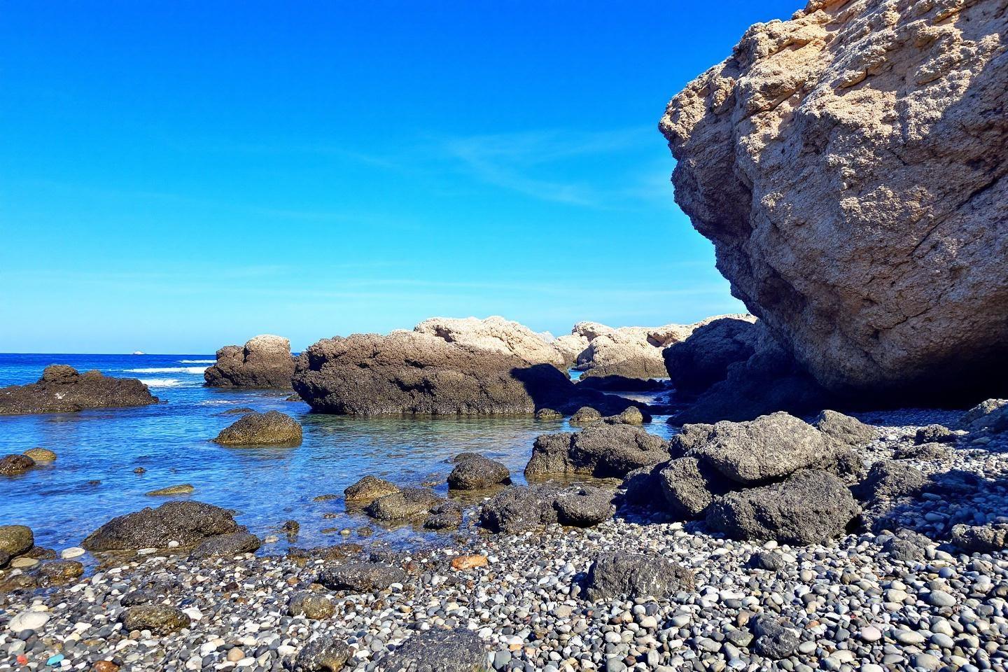 Côte rocheuse aux galets, mer bleue et ciel dégagé